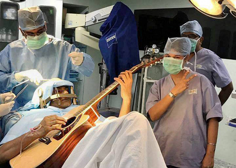 Un musicien joue de la guitare sur la table d'opération à Bengalore (Inde), le 20 juillet 2017.